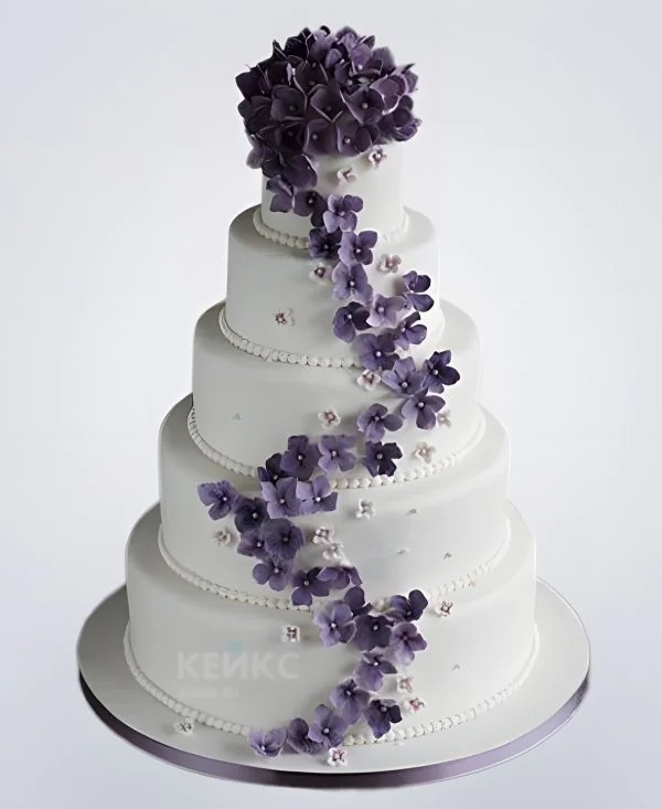 Высокий белый свадебный торт украшенный фиолетовыми цветами Высокий белый свадебный торт украшенный фиолетовыми цветами Фото