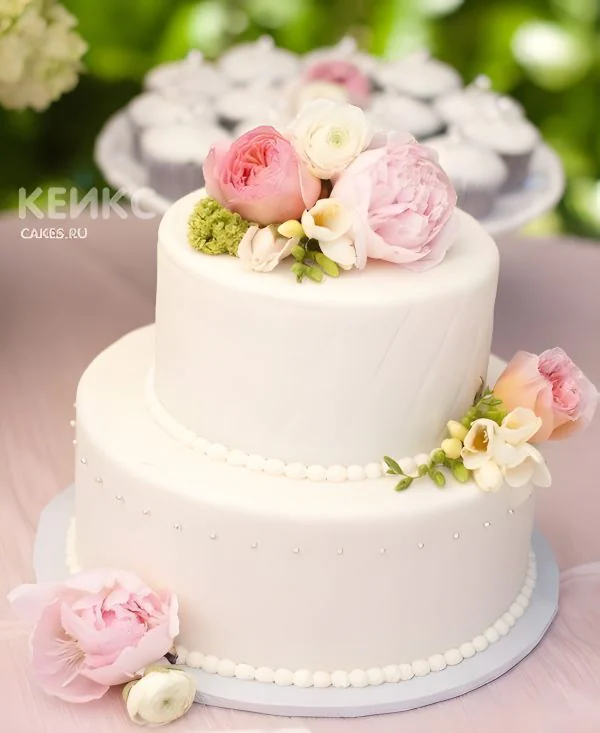 Двухъярусный белый свадебный торт, украшенный живыми пионами Фото