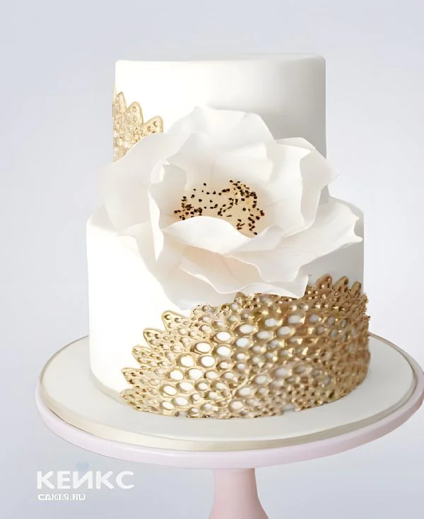 Белый двухъярусный торт с золотым рисунком и цветком Белый двухъярусный торт с золотым рисунком и цветком Фото