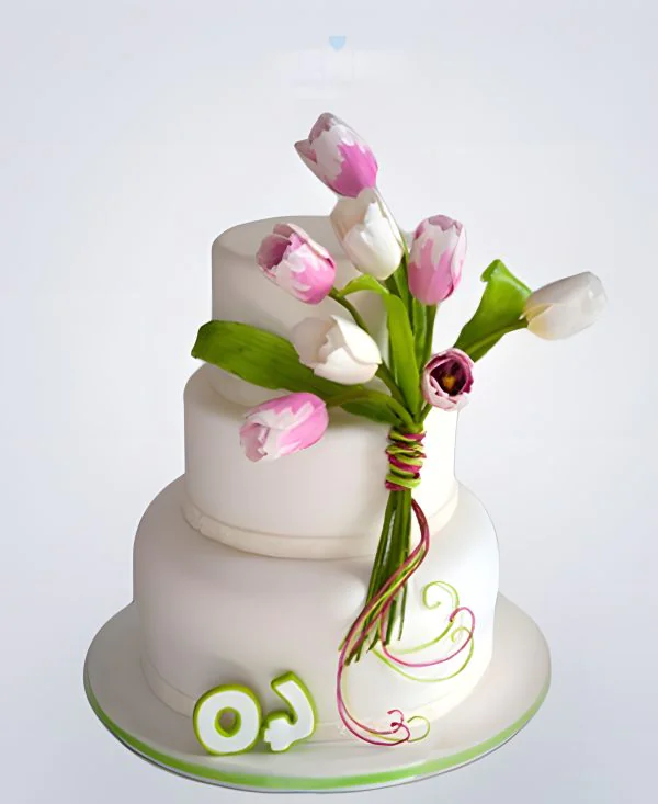 Белый трехъярусный торт украшенный букетом тюльпанов Фото