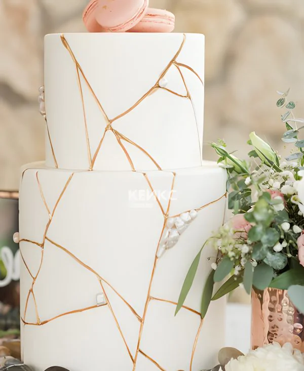 Двухъярусный свадебный торт с мастикой с макарон и узорами из золота Фото