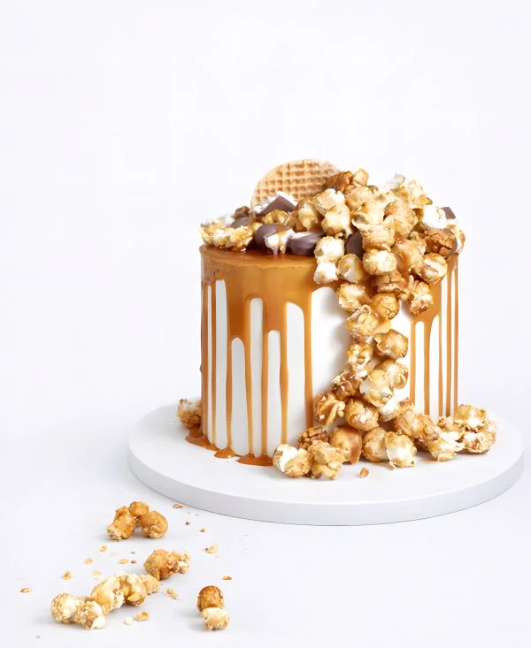 Белый торт с глазурью и попкорном Фото