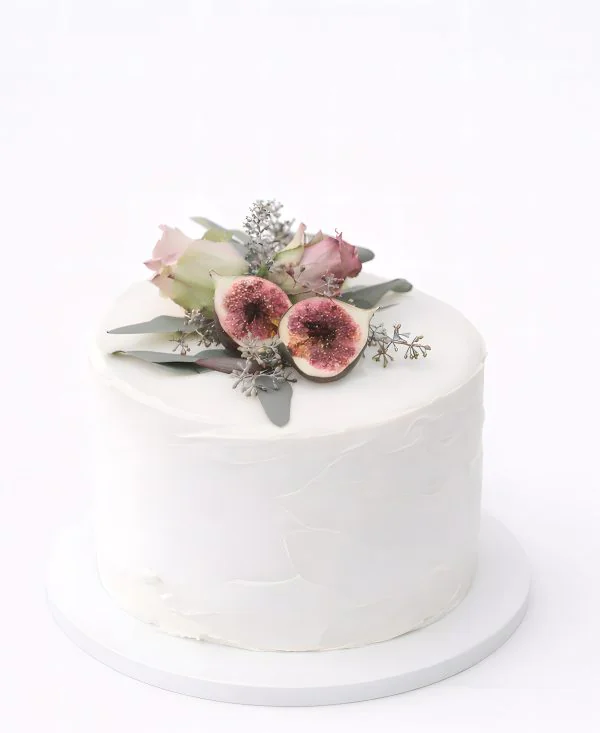 Белый торт украшенный цветами и инжиром Фото